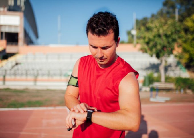 Biegający mężczyzna sprawdza funkcje treningowe w kupionym na promocji tanim zegarku do biegania
