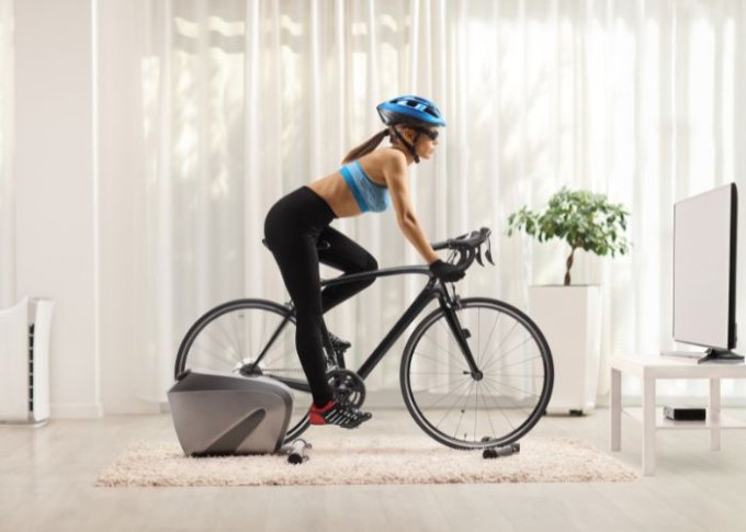 Kobieta wykorzystuje interaktywny trenażer rowerowy do poprawy kondycji