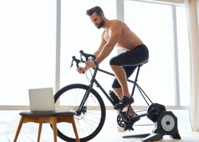Mężczyzna używa profesjonalnego trenażera rowerowego do treningu